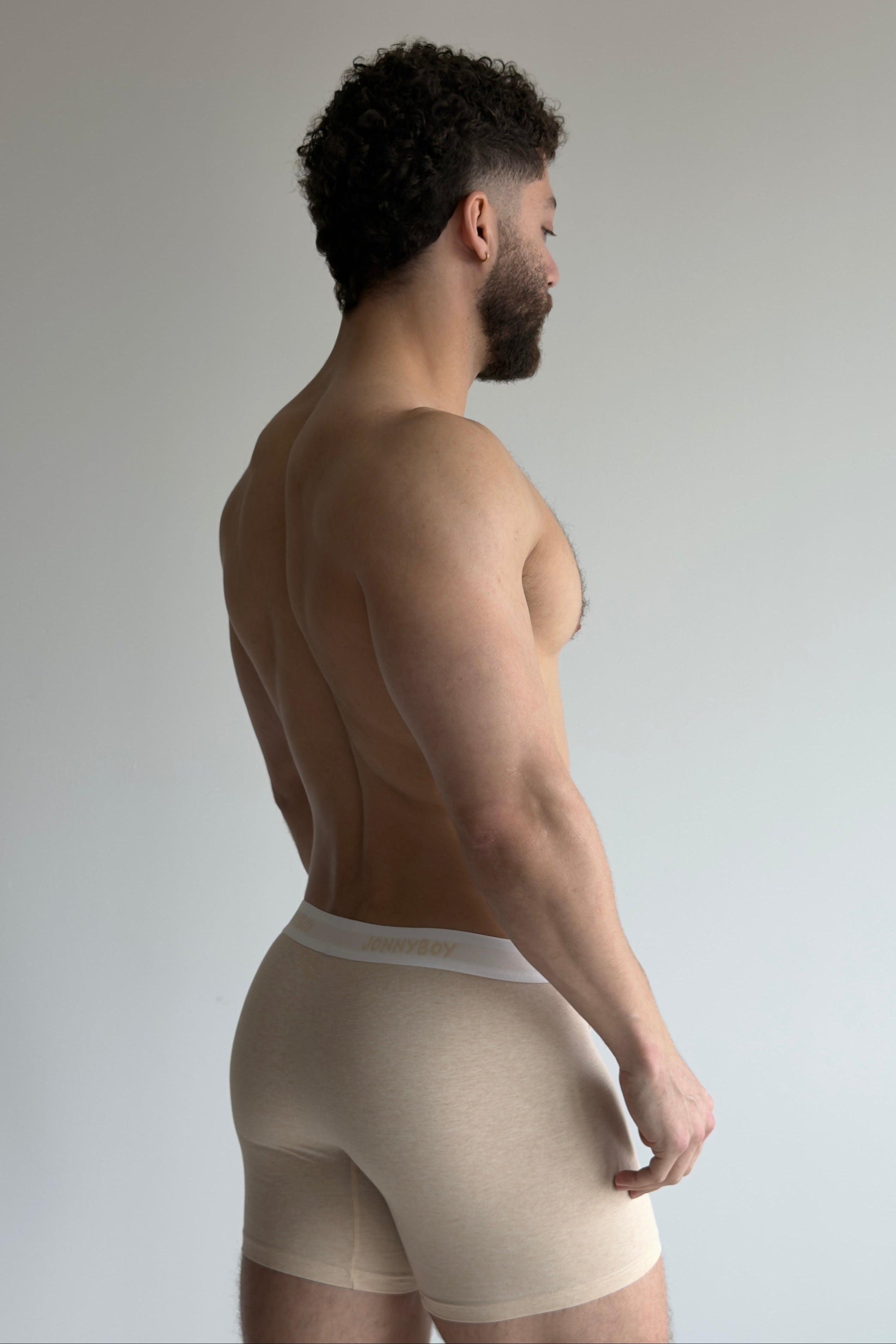 Man wearing beige underwear against a plain background