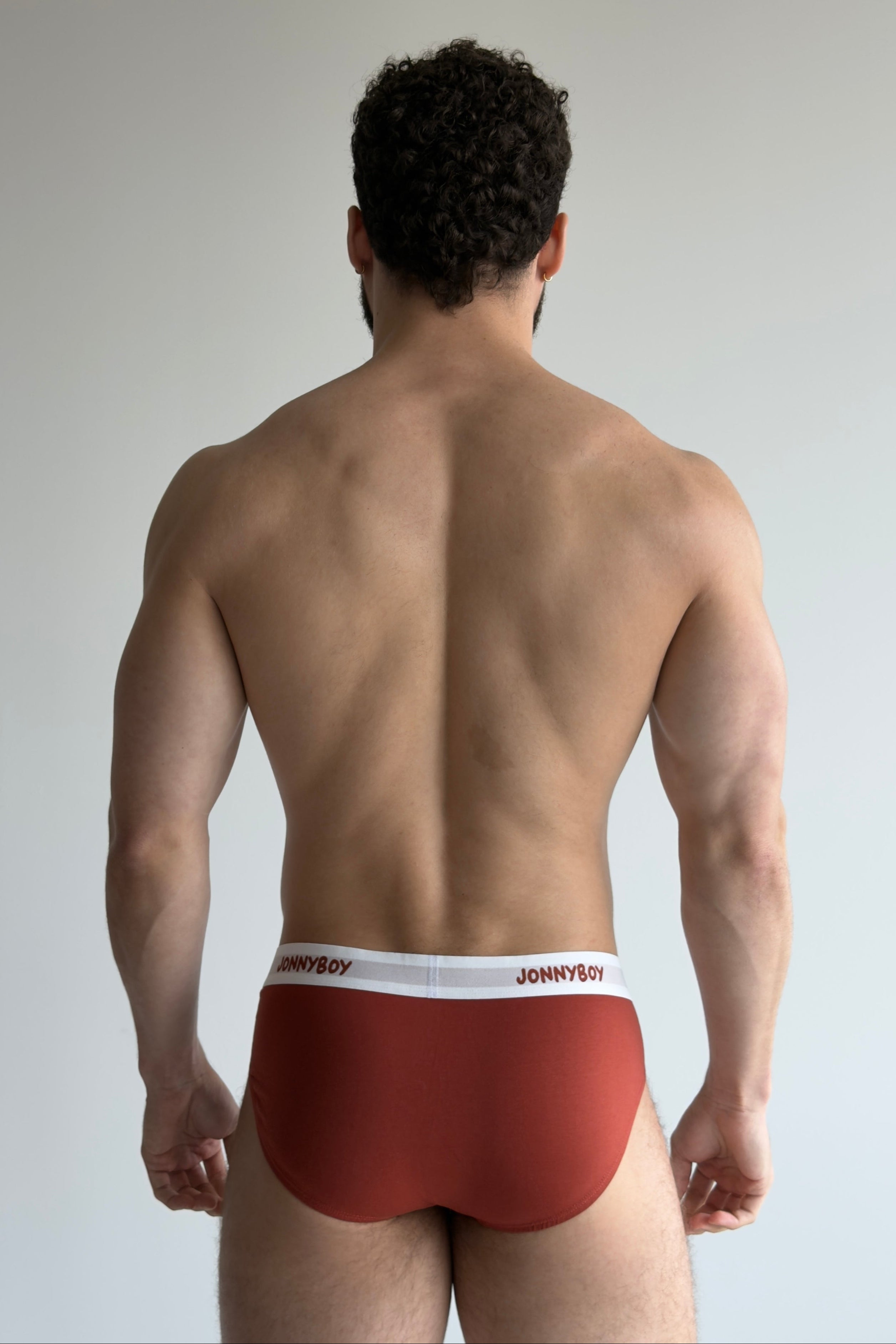 Man wearing red underwear with 'JOHNNYBOY' brand label on a plain background